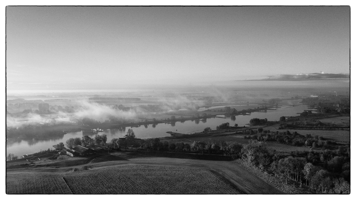 Zwart-wit luchtfoto van de Rijn in de ochtendmist